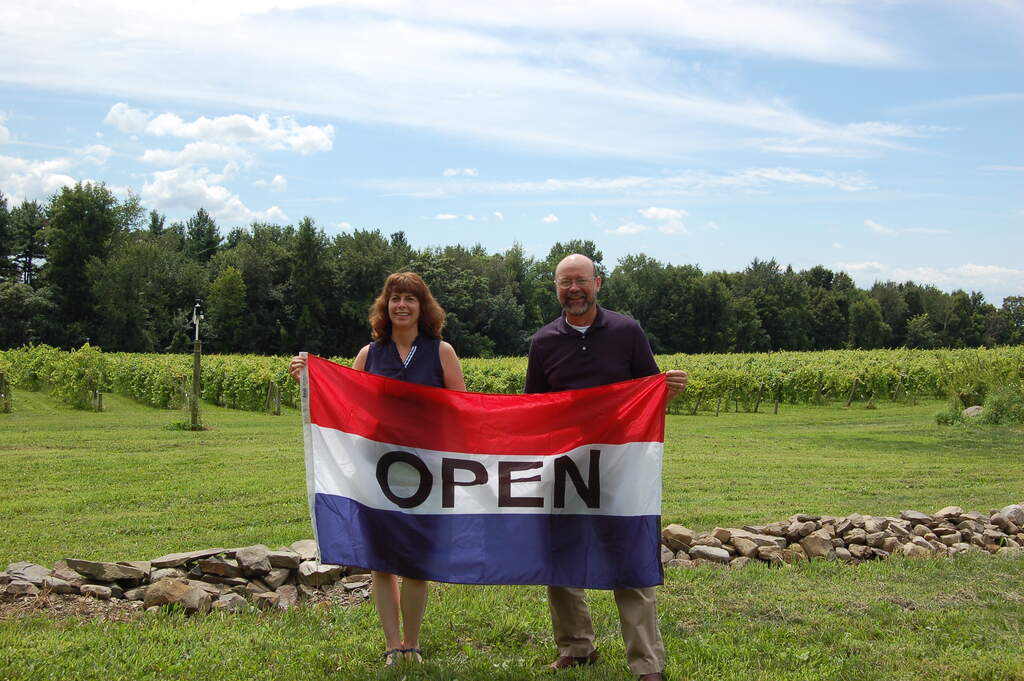 Mary and Gerry hold an open flag when they opened their winery in August 2013.